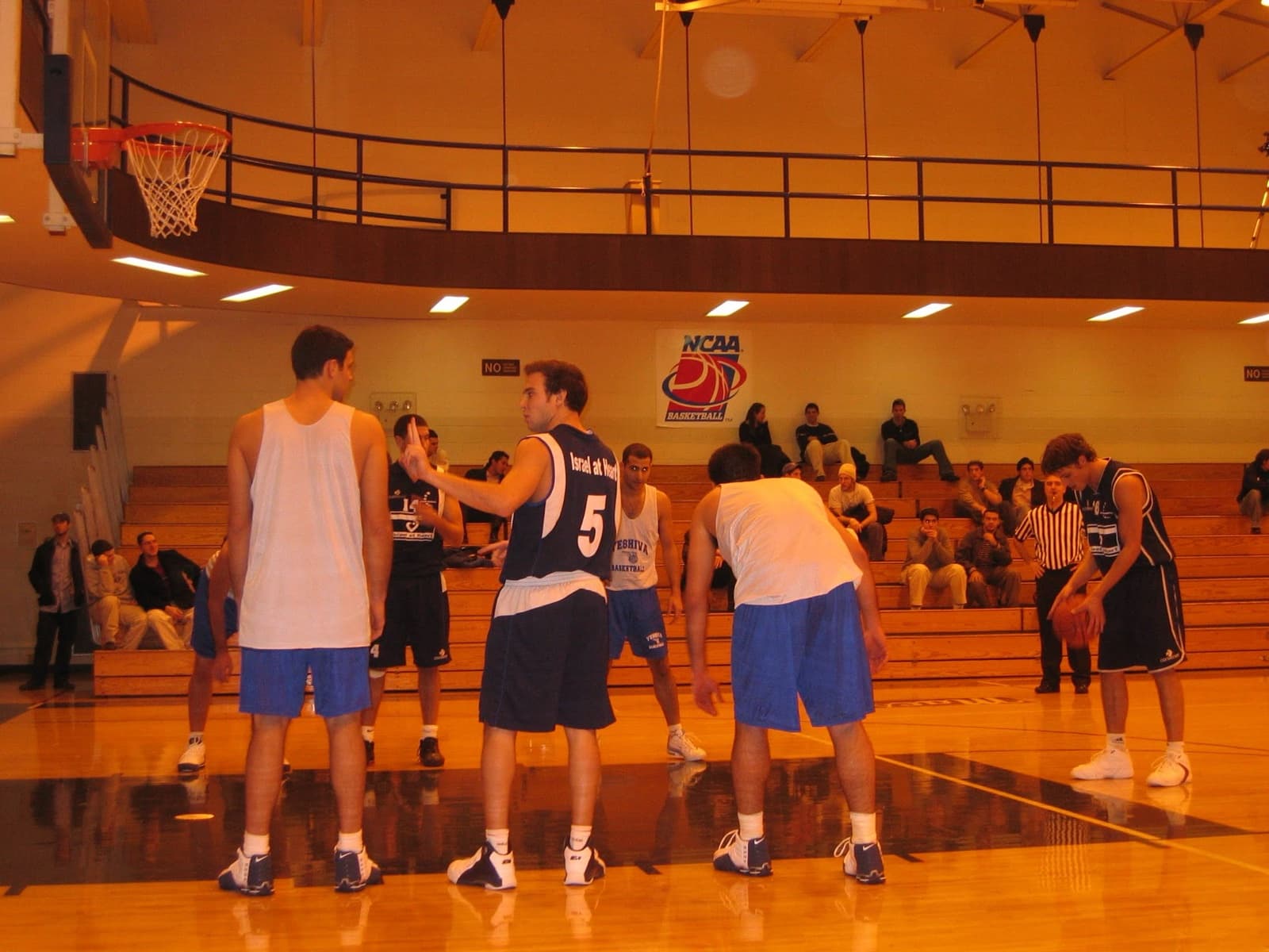 Israel at Heart players in navy jerseys line up against an American college team during an NCAA game.