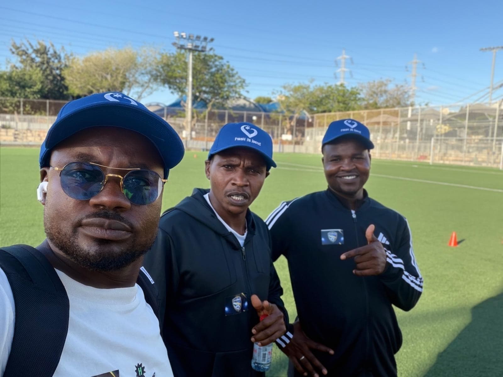 Three coaches on the pitch wearing Israel at Heart caps.