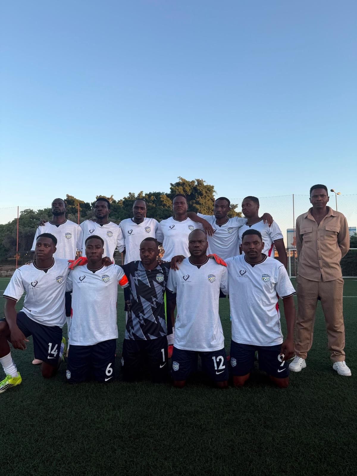 A refugee soccer team posed together in their kits on the field.