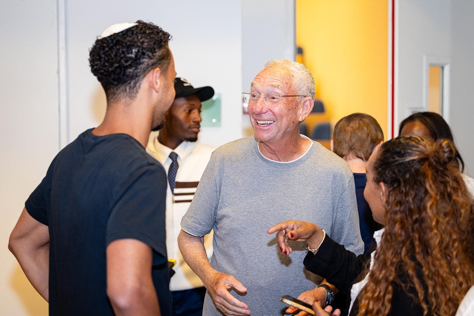 Joey Low laughing in conversation with a group of students.
