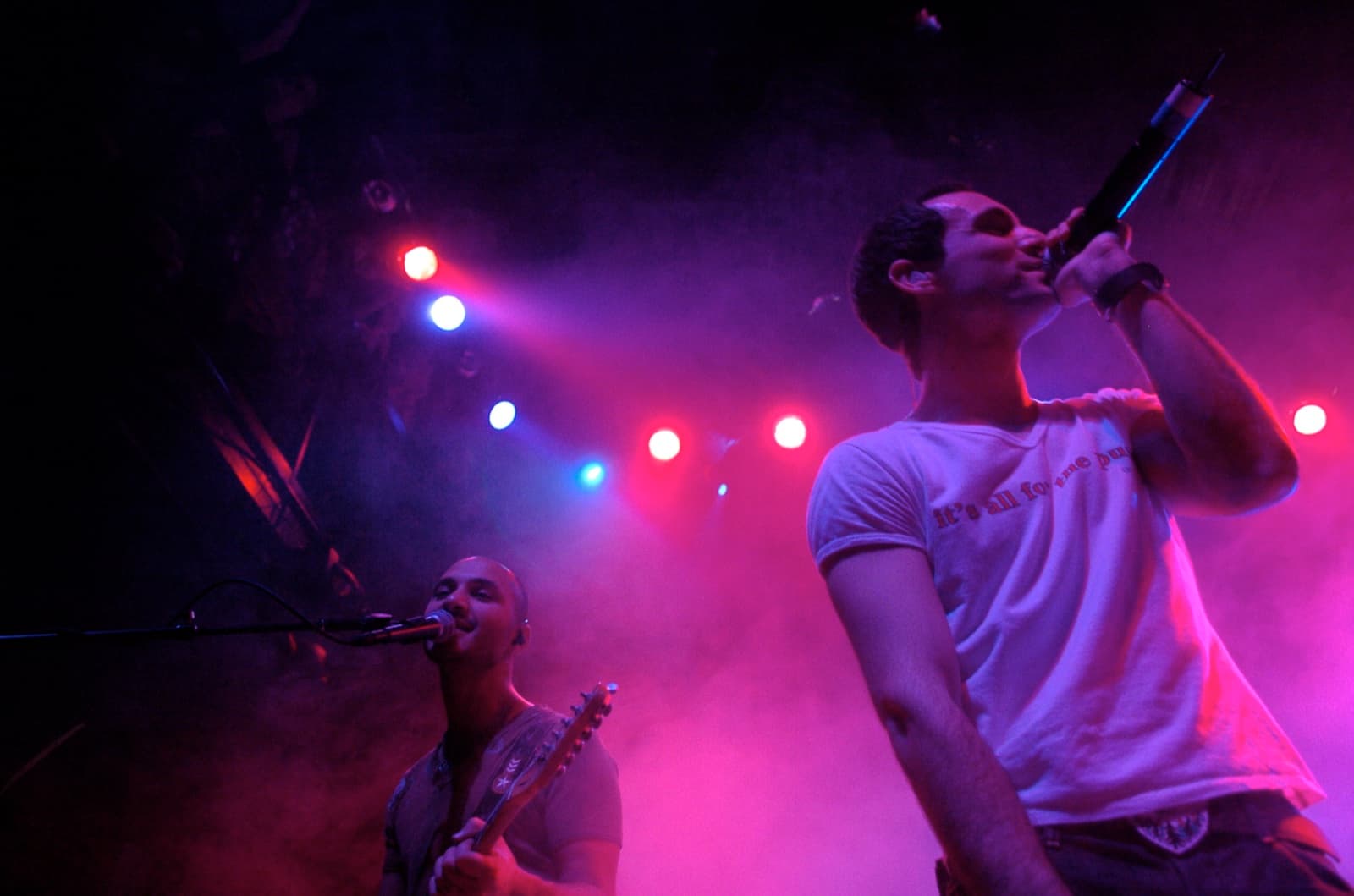 Ivri Lider singing into the microphone under pink and purple stage lights.