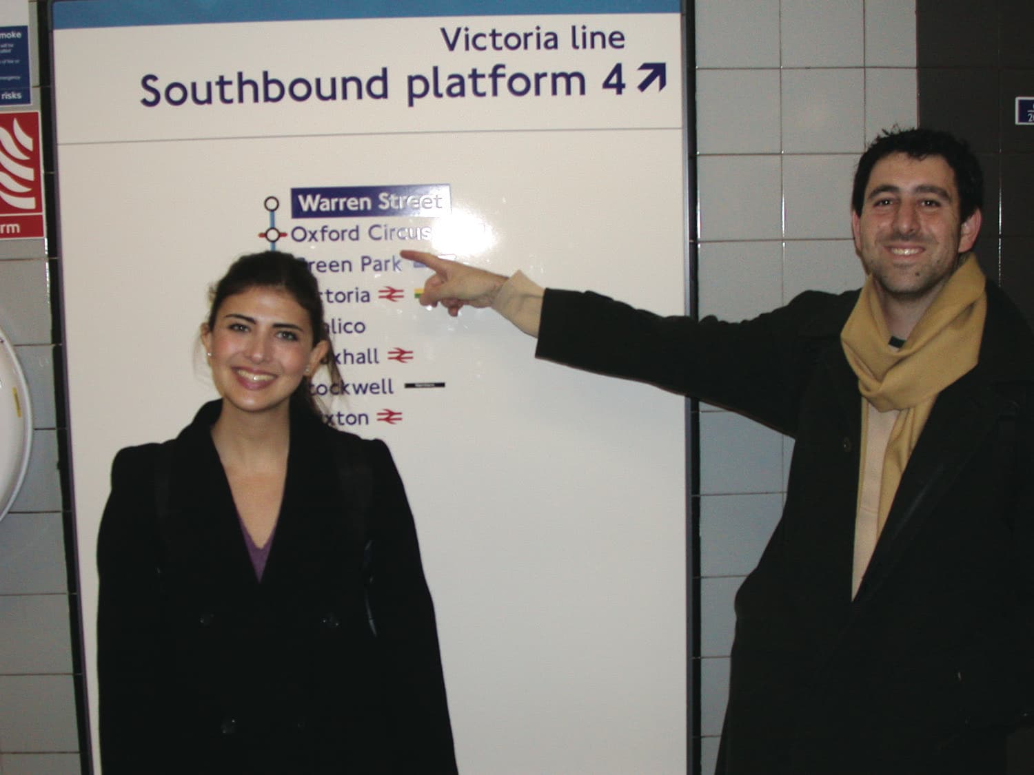 Two delegates on the London Underground, pointing at a line map.