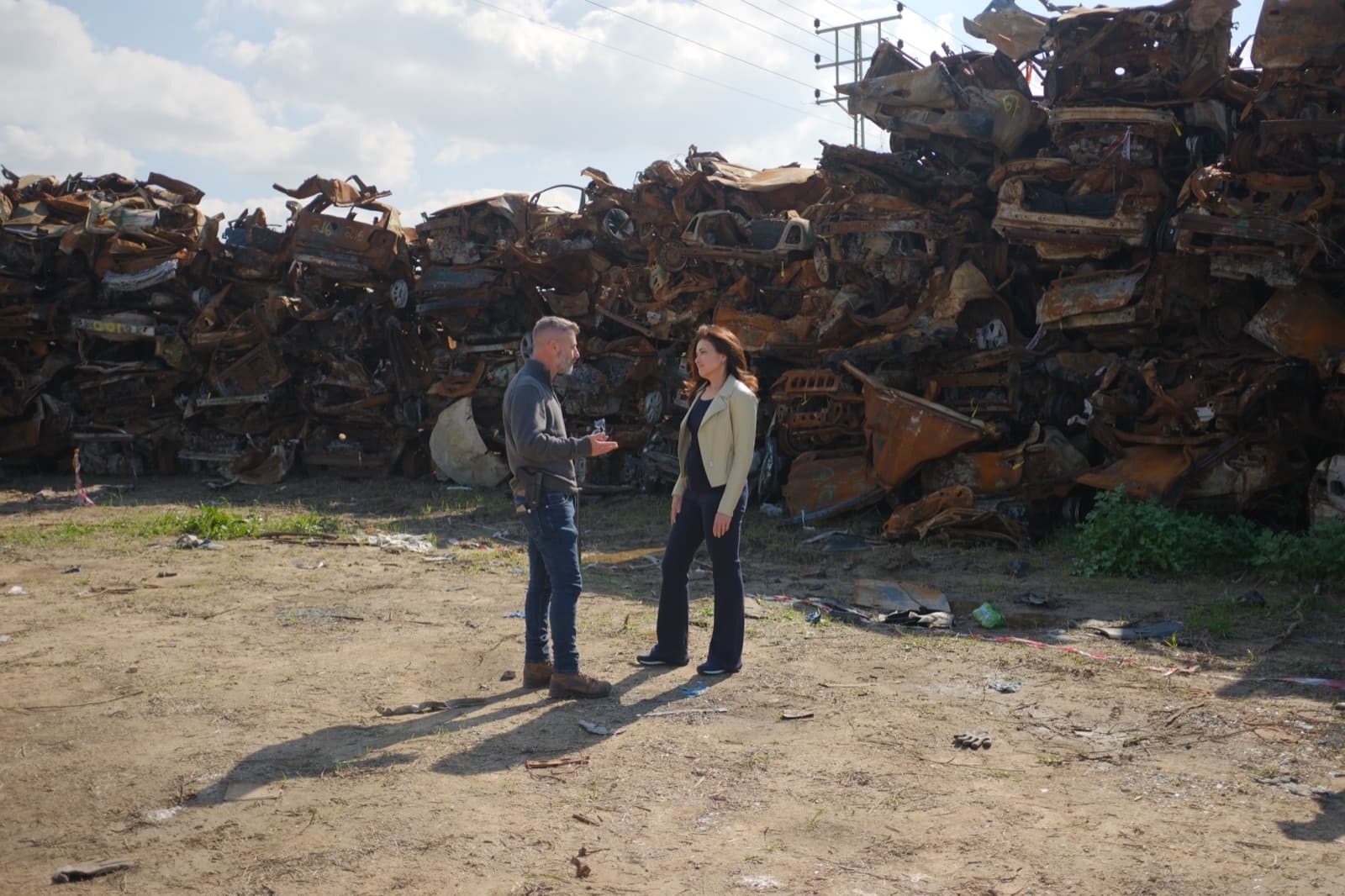 Sheryl Sandberg speaking with Eran Masas before a large pile of vehicles destroyed on October 7.