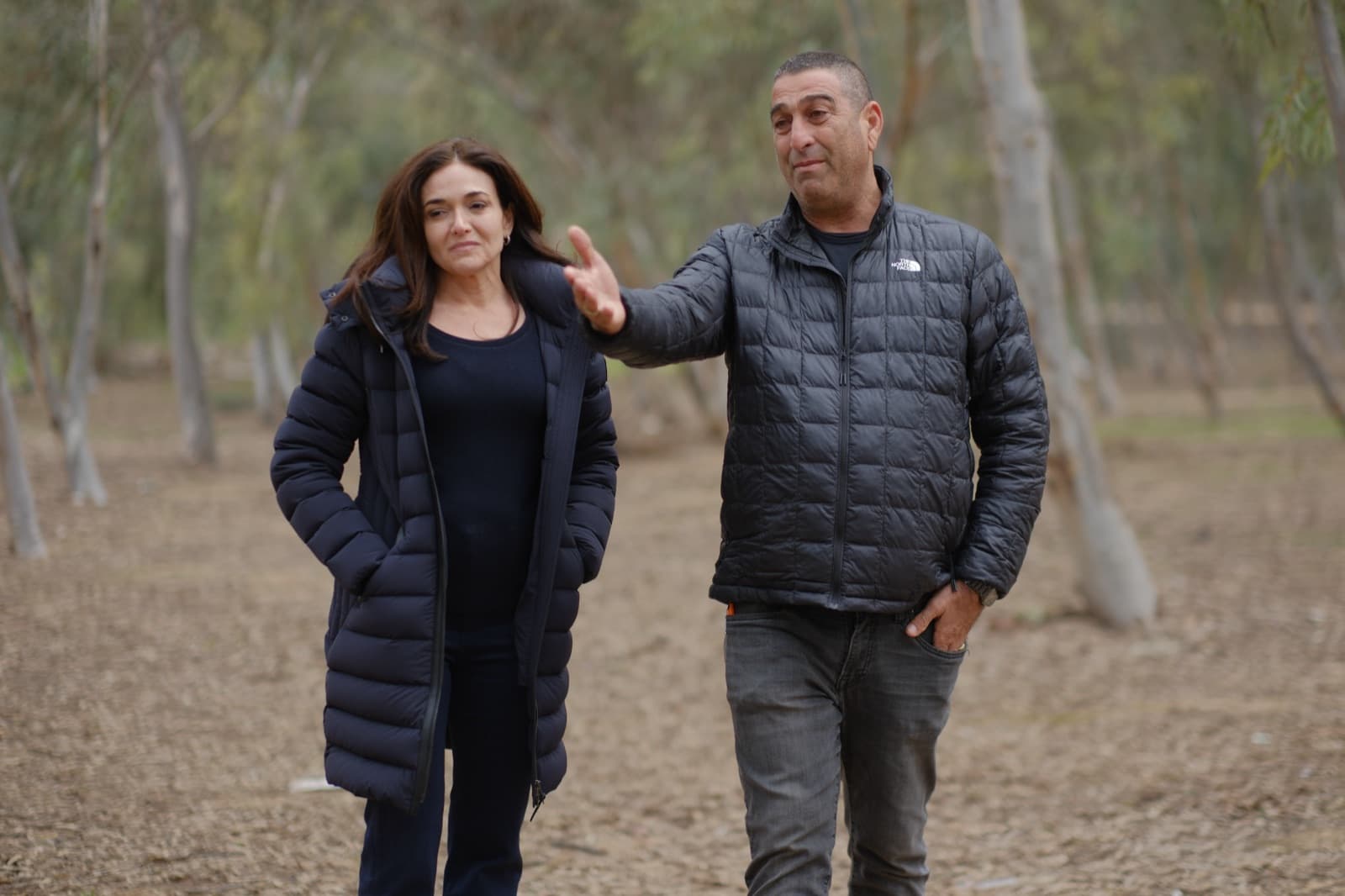 Sheryl Sandberg walking with Rami Davidian in a grove near the Nova festival site.