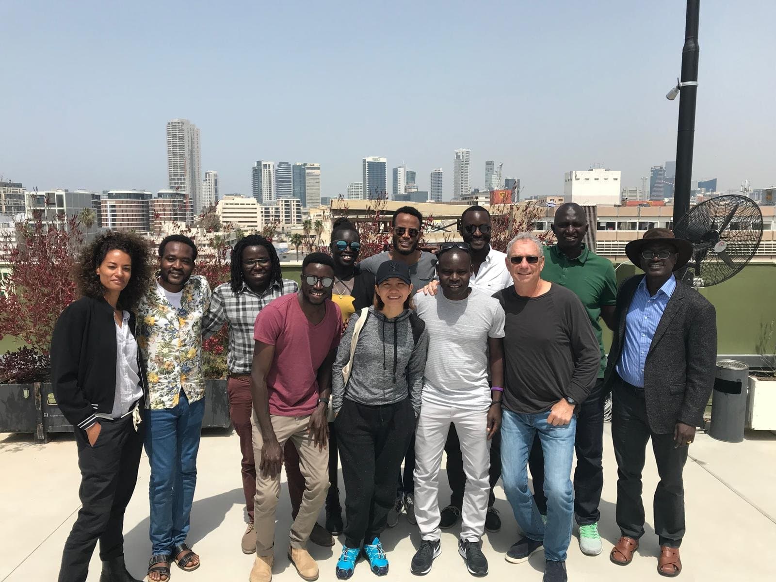 African students gathered on a rooftop with the Tel Aviv skyline behind them.