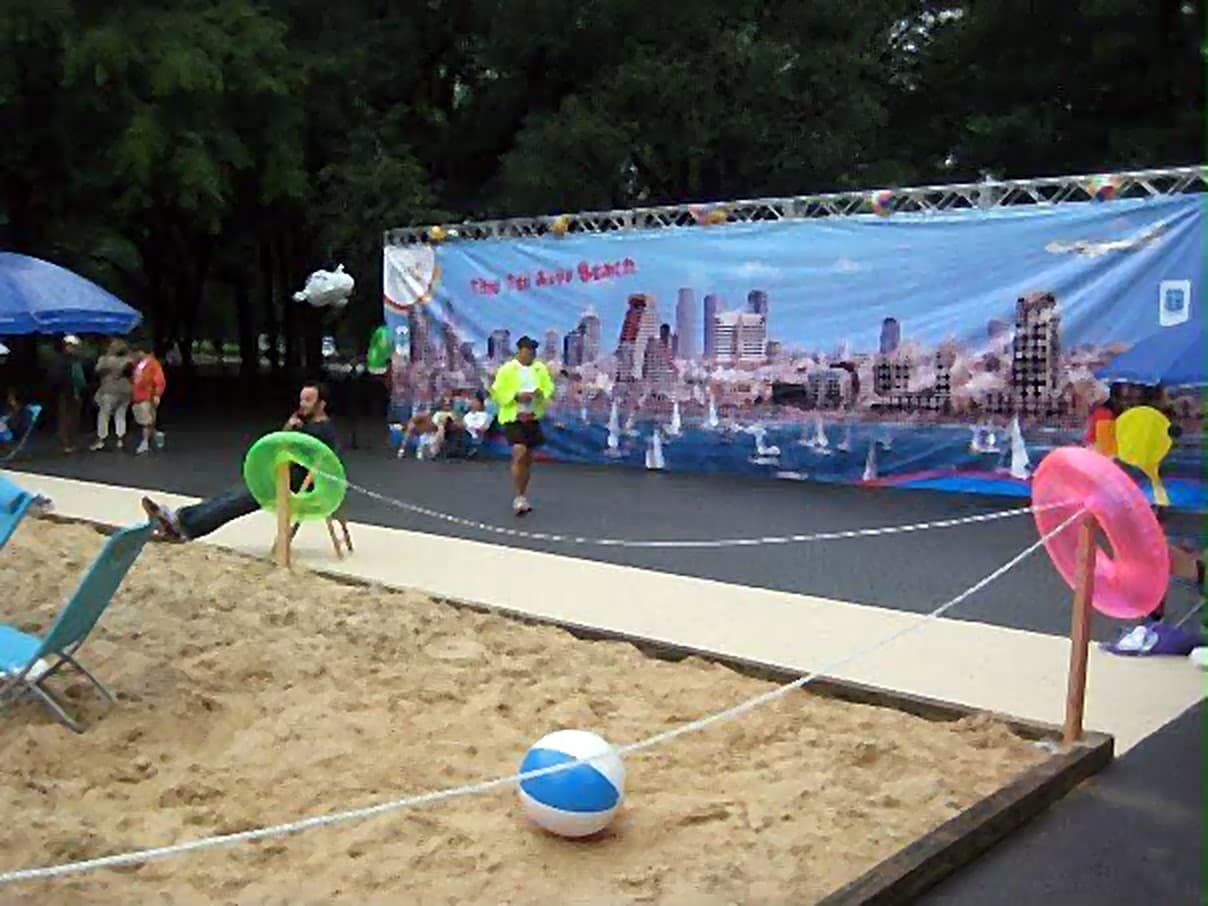 Sand, umbrellas, beach chairs, and beach balls laid out in Central Park beneath a banner showing the Tel Aviv skyline.